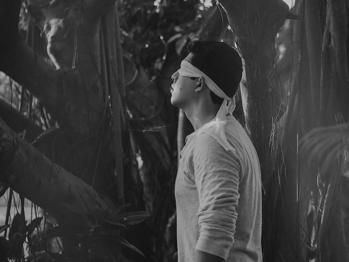 A man blindfolded in the woods A woman prays in the pews of a mostly empty Church, showing how combatting racism in the United States must be a spiritual battle